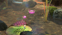 An early screenshot of Winged Pikmin carrying pink pellets above water.