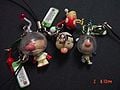 Three Pikmin key chain/cell phone strap products. One depicting Olimar and a Red Pikmin, one of the President and a Bulbmin, and one of Louie and a White Pikmin.