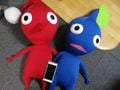 A Red Pikmin and Blue Pikmin plush compared to a smartphone.