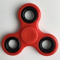 Real world image of a red fidget spinner.